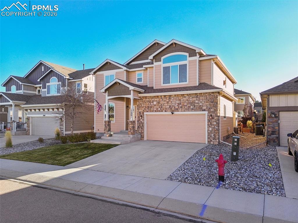 Image 3 of 38: Craftsman-style home with a garage, stone siding, and concrete driveway