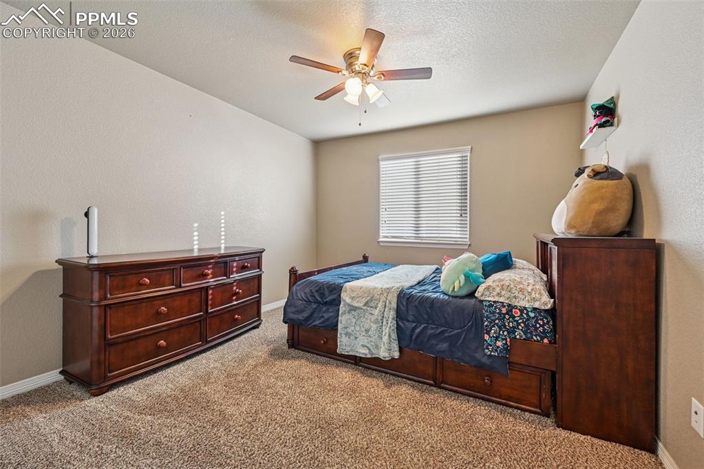 Image 30 of 38: Carpeted bedroom featuring a ceiling fan, a textured wall, and a textured c