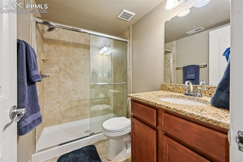 Image 36 of 38: Bathroom with a textured ceiling, a textured wall, vanity, a shower stall,