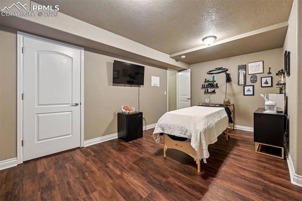 Image 37 of 38: Bedroom featuring a textured ceiling and dark wood-style floors