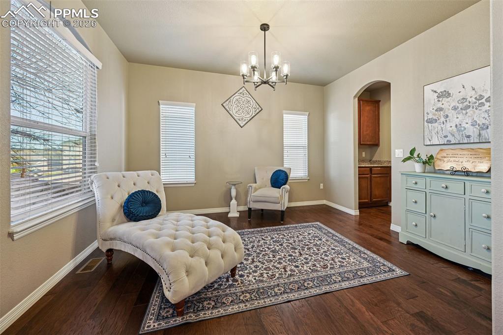 Image 9 of 38: Living area featuring arched walkways, dark wood-style flooring, and hangin