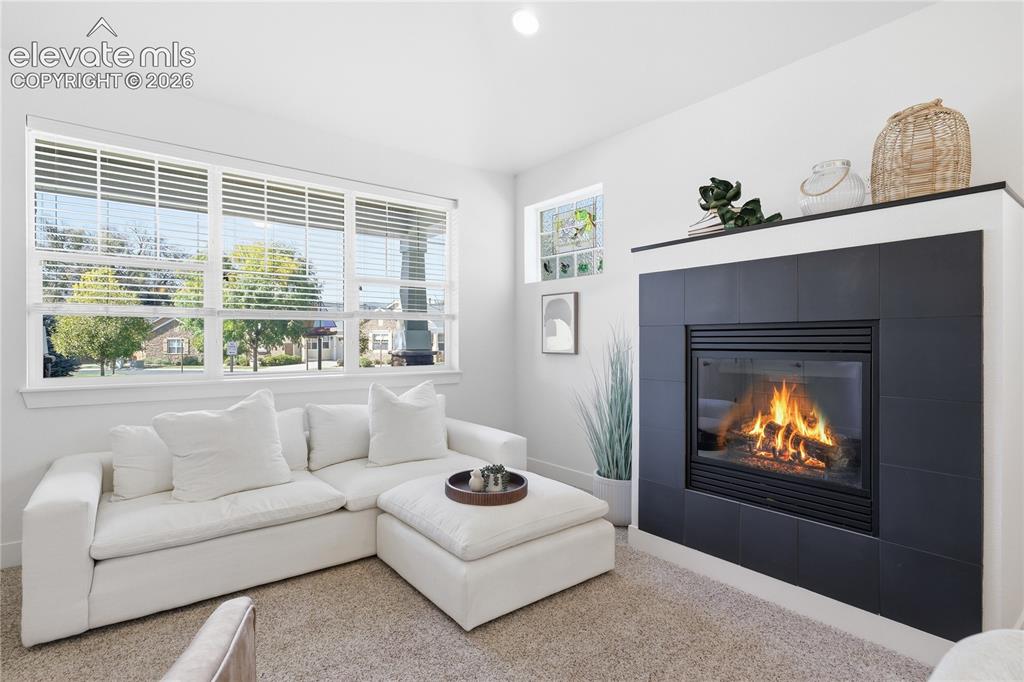 Image 12 of 24: Fireplace with black tile surround and mantle, framed by a large multi-pane