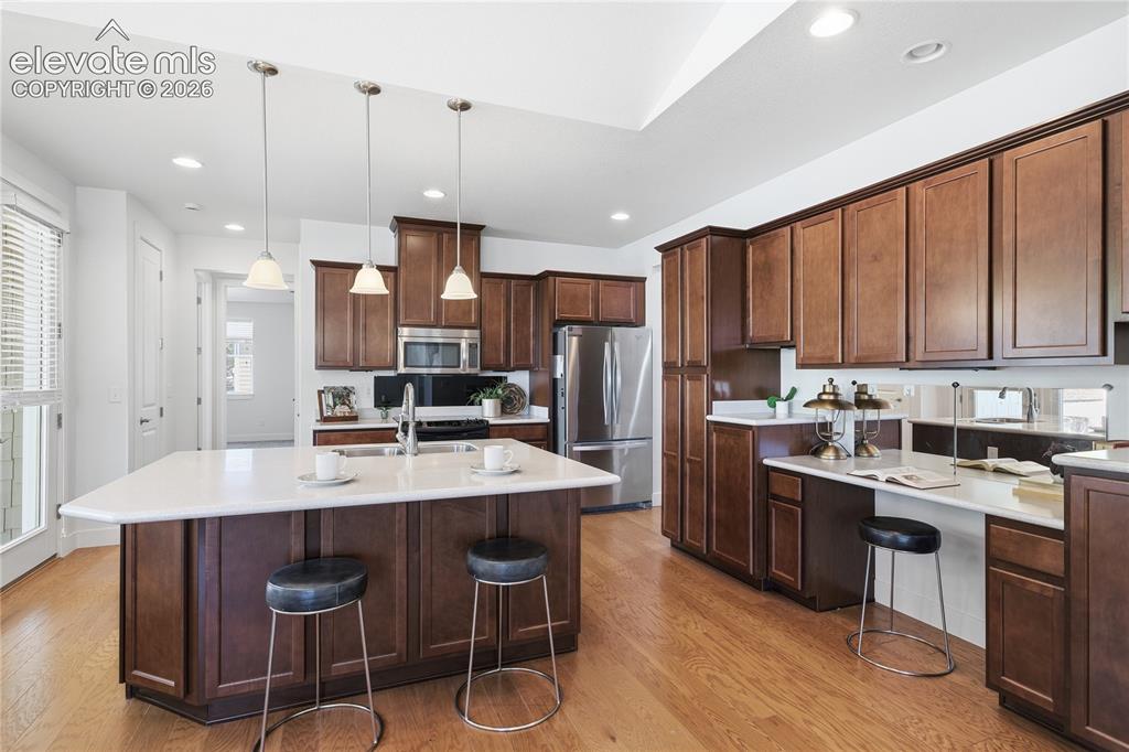 Image 13 of 24: Kitchen featuring wood-finish flooring, dark wood cabinetry, stainless stee