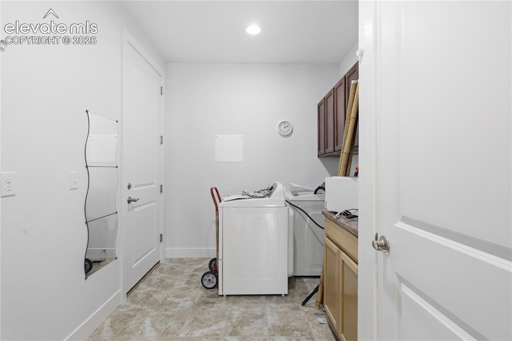 Image 17 of 24: Dedicated laundry room featuring front-load washer and dryer, wood-finish c