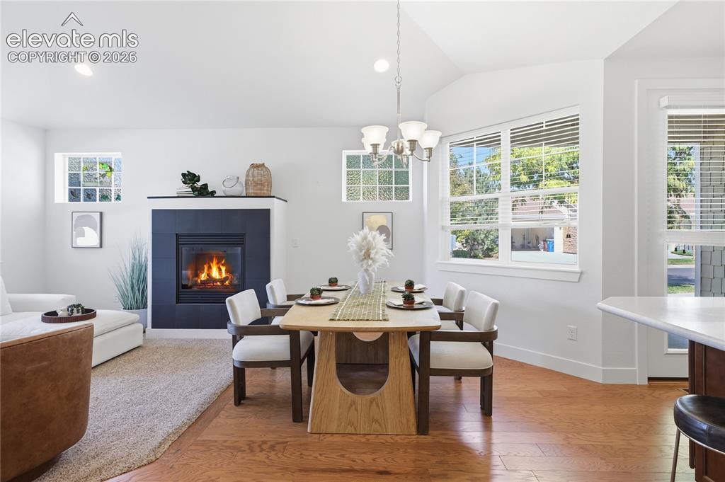 Image 18 of 24: Bright, open living space featuring hardwood flooring, a wood-burning firep
