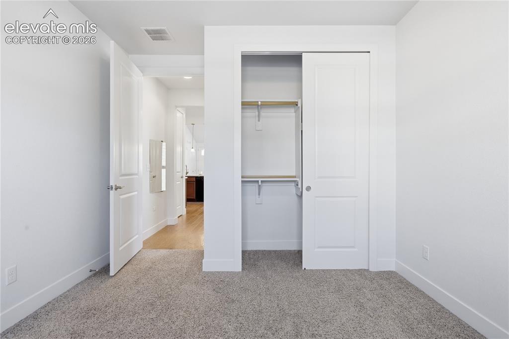Image 21 of 24: Plush carpeted flooring, white walls, built-in closet with sliding doors, a