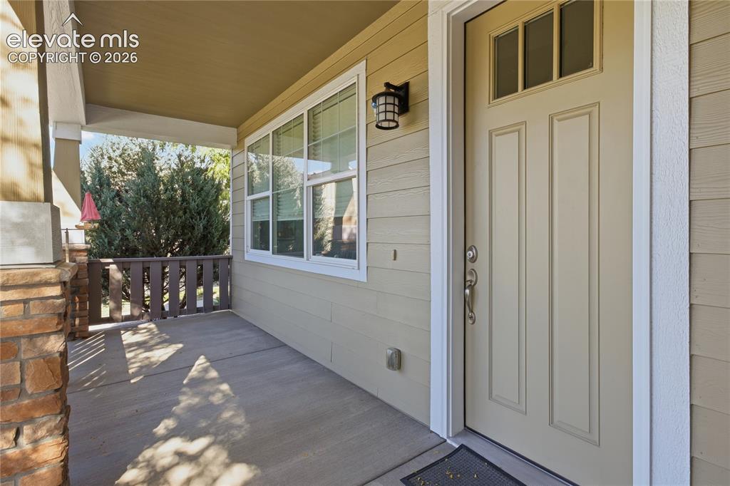 Image 23 of 24: Covered front porch featuring a stone and wood column, a paneled entry door