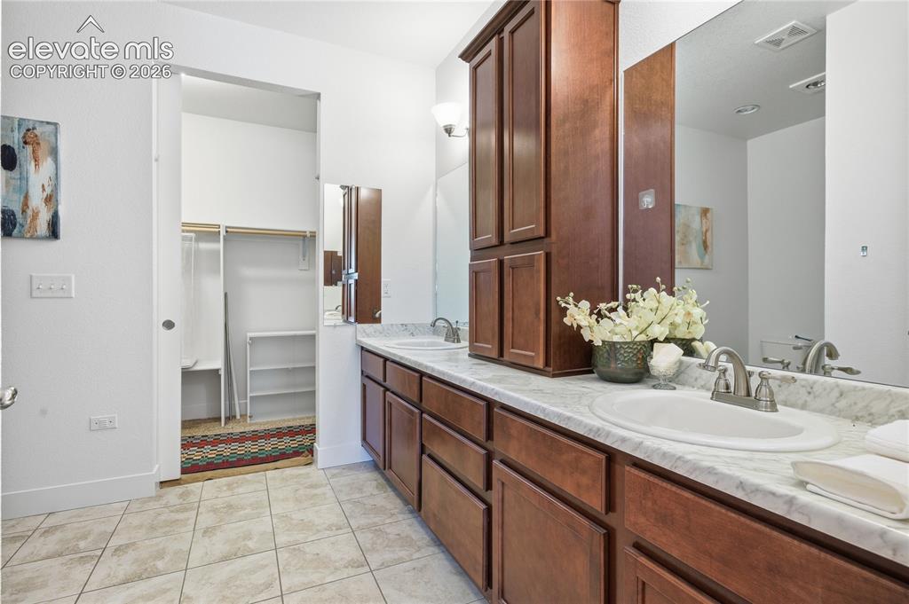 Image 6 of 24: Dual vanity with integrated sinks, wood-finish cabinetry, and a full-width