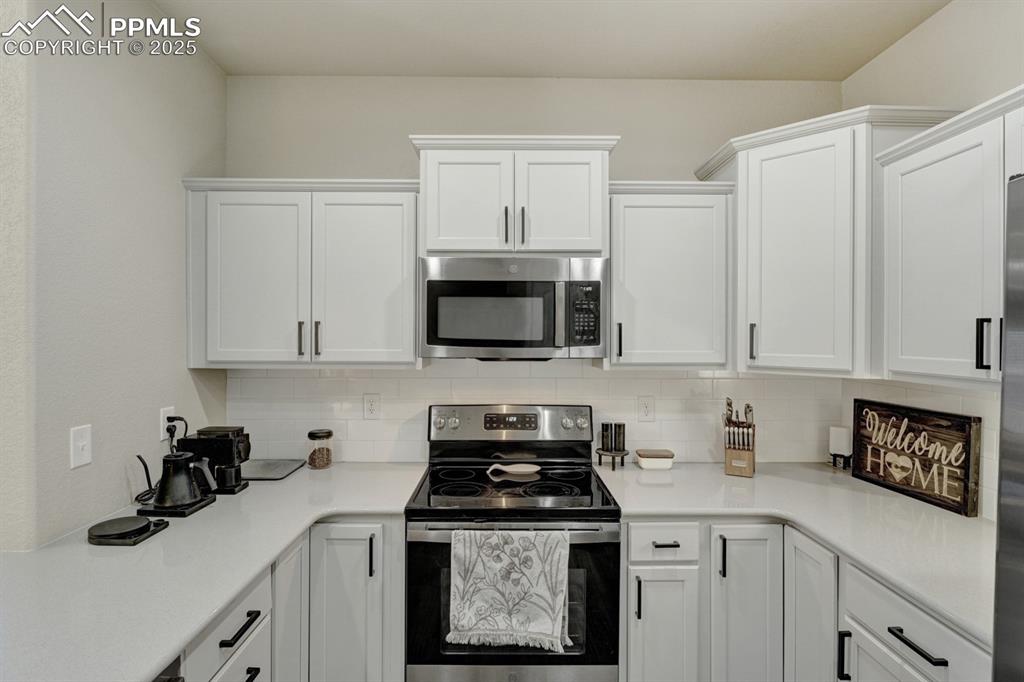 Image 10 of 25: There is ample storage space in the beautiful white modern cabinetry.