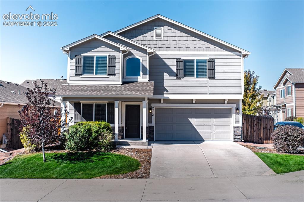 Caption: Two-story residence featuring a gray exterior with shingle and siding accents, a covered entry porch