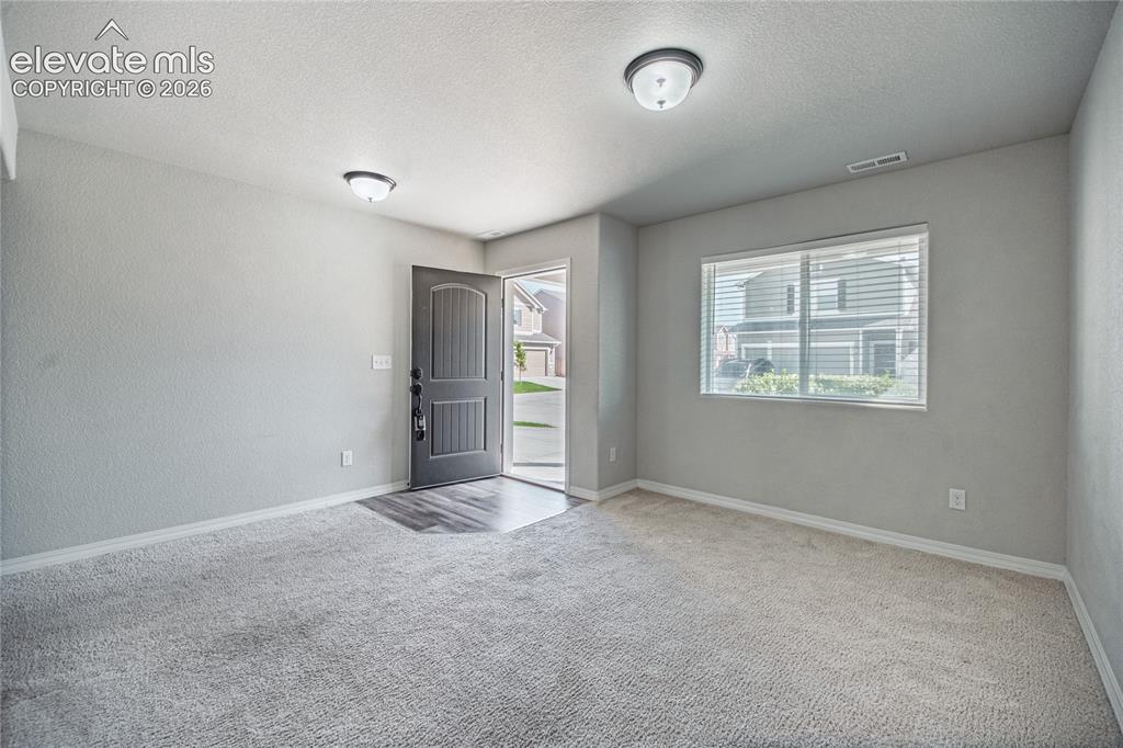 Image 12 of 35: Entryway featuring a dark paneled door, wood-finish flooring, light gray ca