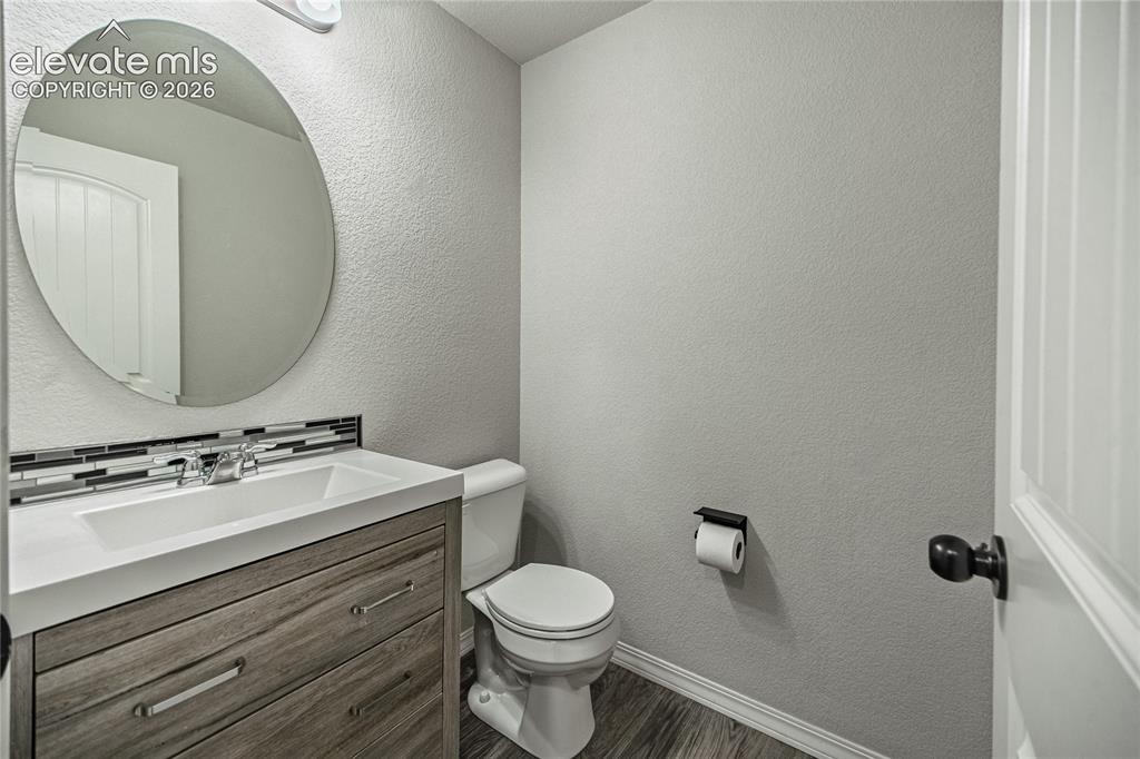 Image 15 of 35: Contemporary vanity with wood-finish cabinetry, integrated sink, and mosaic