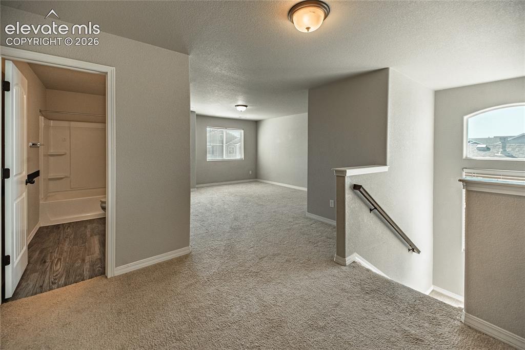 Image 16 of 35: Neutral-toned carpeting throughout, white trim, and a white interior door w