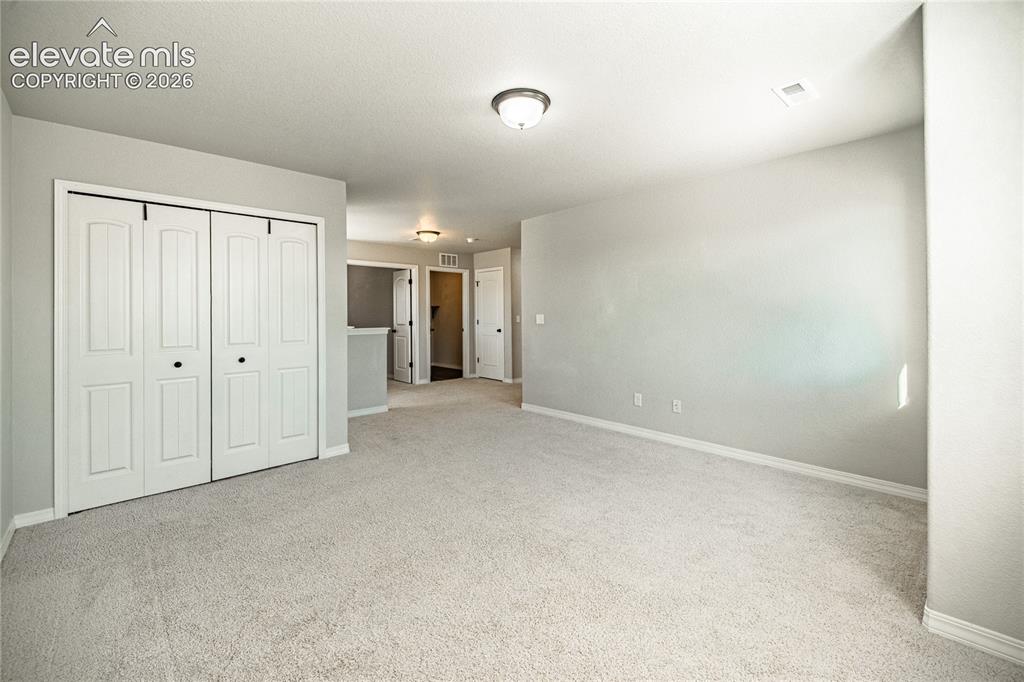 Image 17 of 35: Wall-to-wall carpeting in a neutral tone, bi-fold closet doors, white baseb