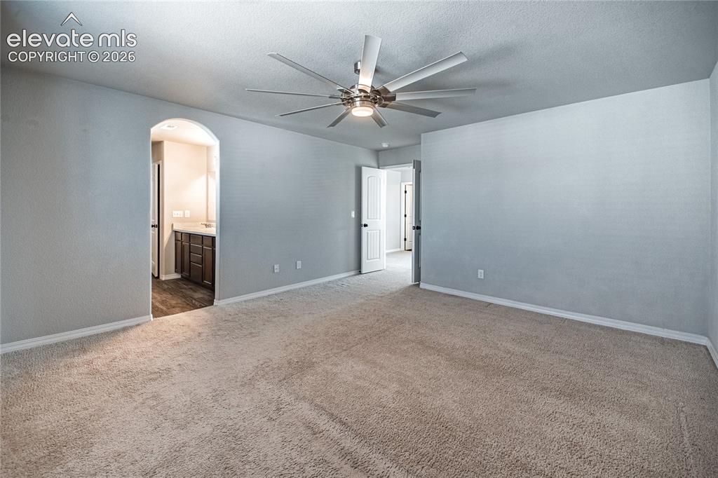 Image 19 of 35: Spacious room with neutral-toned carpeting, a contemporary ceiling fan, and