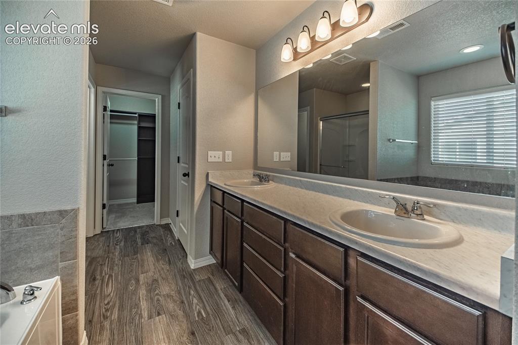 Image 20 of 35: Dual vanity with integrated sinks, wood-finish flooring, a large mirror, an