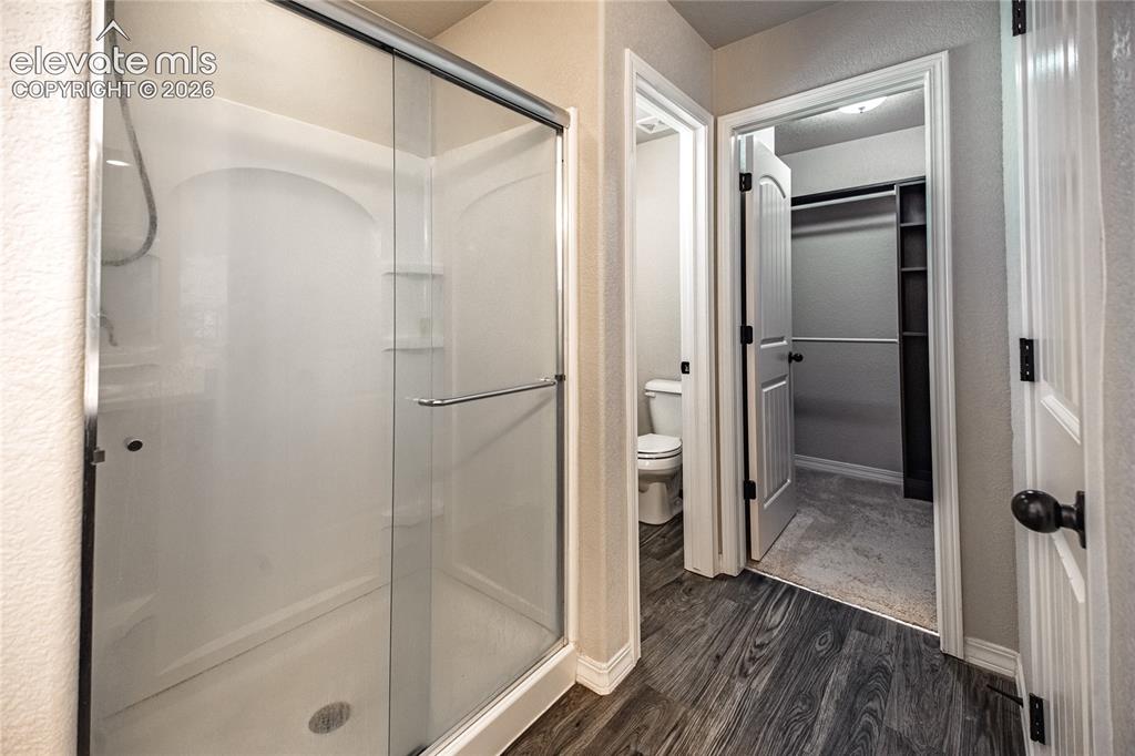 Image 22 of 35: Glass-enclosed shower with integrated shelving, wood-finish flooring, and b