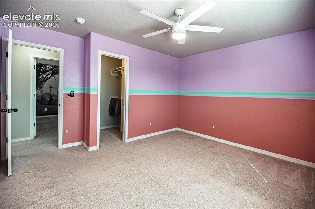 Image 26 of 35: Textured wall finishes with a decorative accent stripe, ceiling fan, and pl
