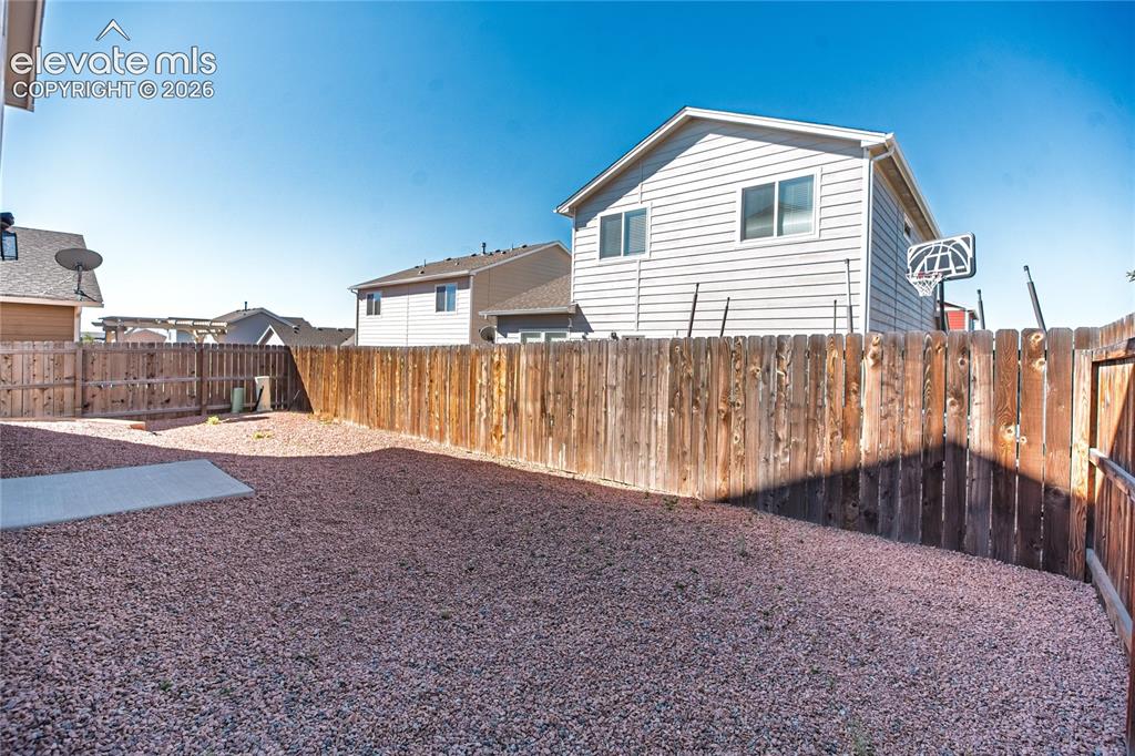 Image 30 of 35: Expansive backyard featuring a gravel surface, wood privacy fencing, and a