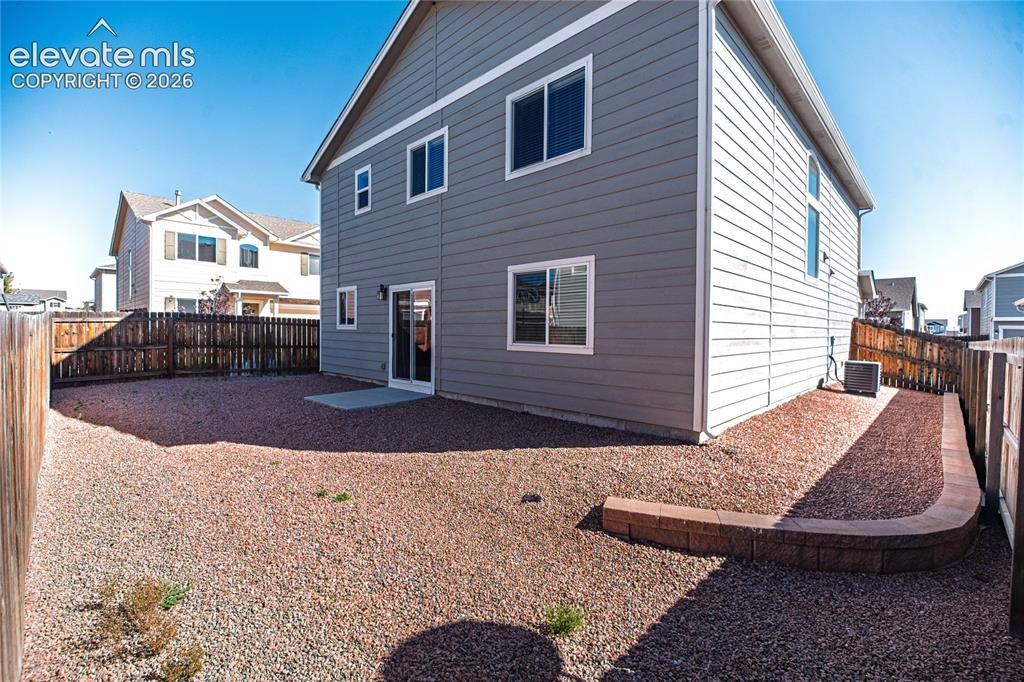 Image 32 of 35: Gray horizontal siding with white trim, sliding glass door, and a low retai