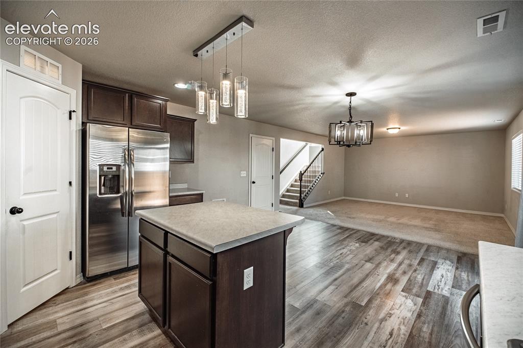 Image 6 of 35: Kitchen island with solid surface countertop, wood-finish flooring, stainle