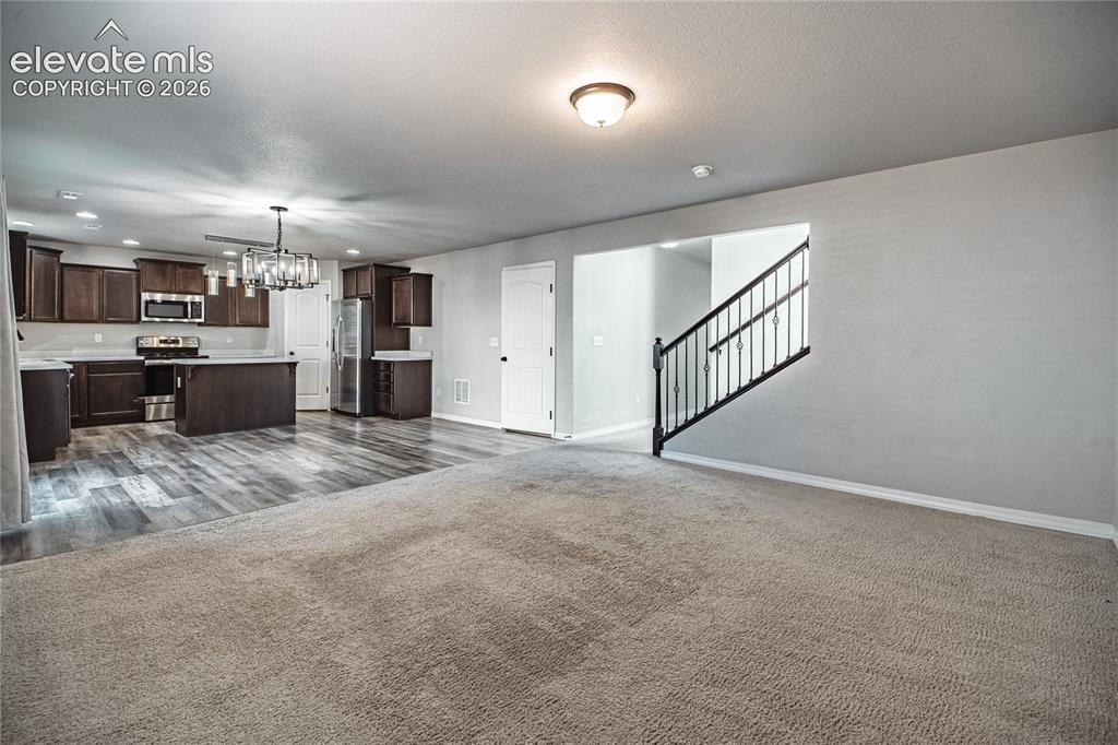 Image 9 of 35: Open-concept living area featuring a kitchen with dark wood-finish cabinetr