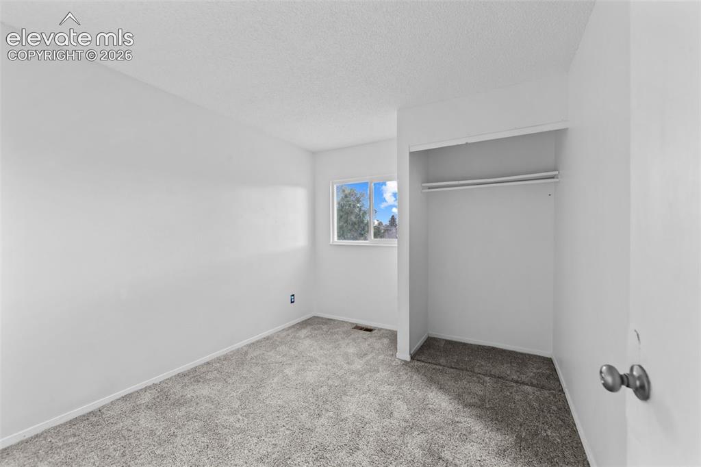 Image 11 of 20: Bright interior space featuring light gray textured carpeting and white pai