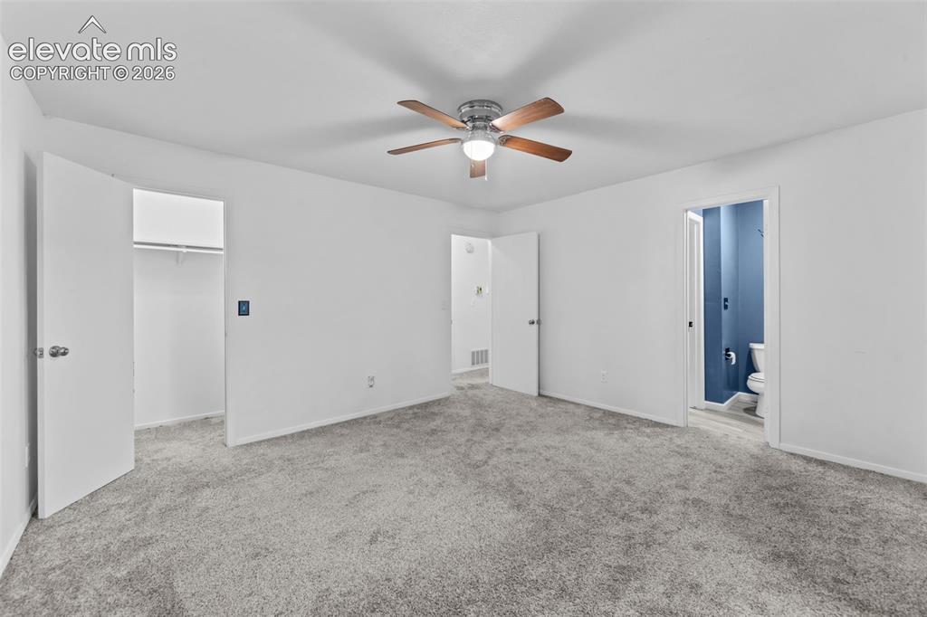 Image 14 of 20: Spacious room featuring neutral carpeting, white walls, a ceiling fan with 