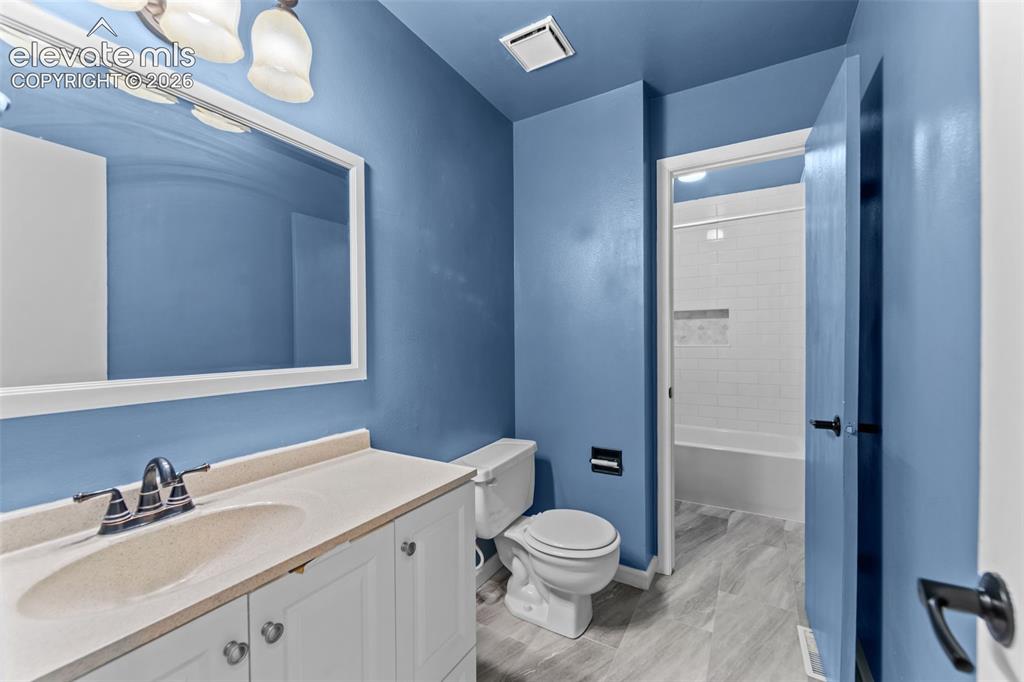 Image 16 of 20: Bathroom featuring a single vanity with a solid surface countertop, white c