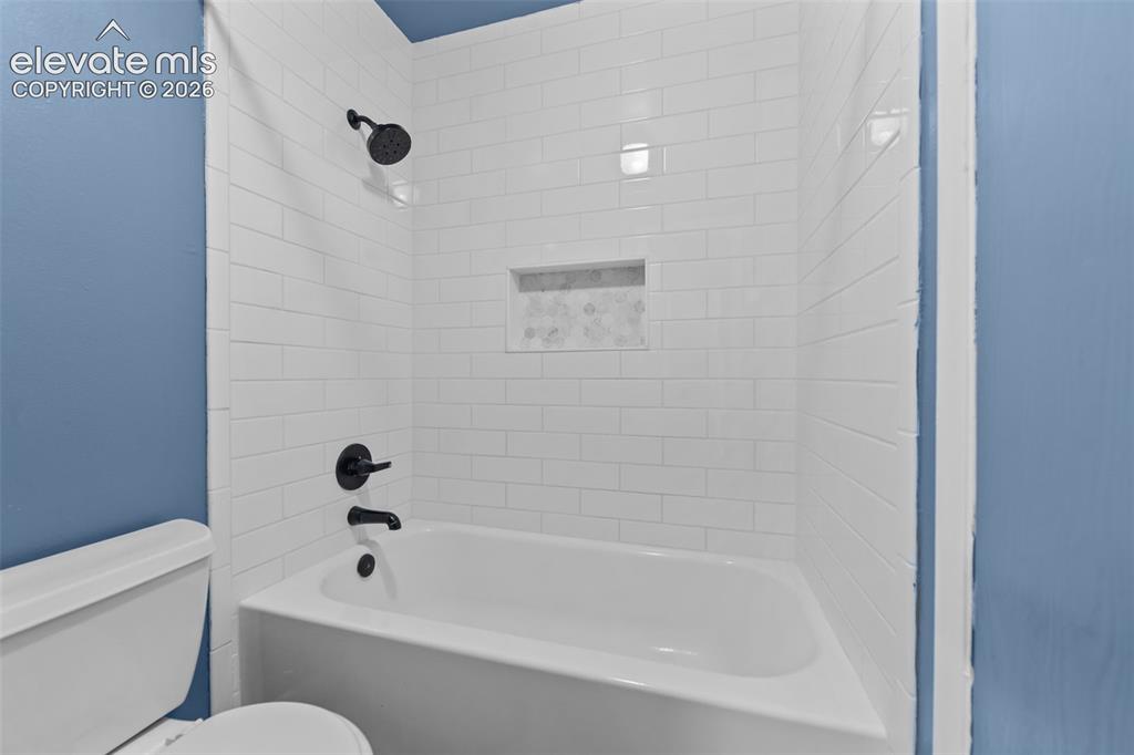 Image 17 of 20: Bathtub with white subway tile surround, matte black shower fixtures, and a