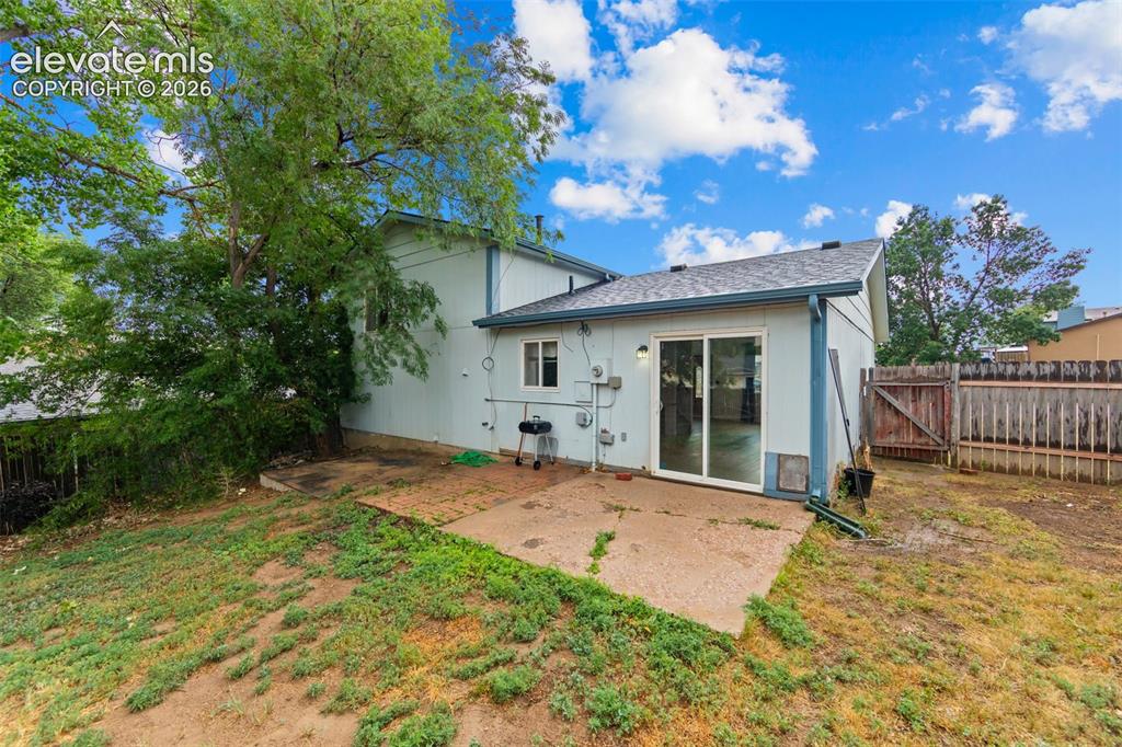 Image 20 of 20: Rear exterior with a concrete patio, sliding glass door entry, pitched shin
