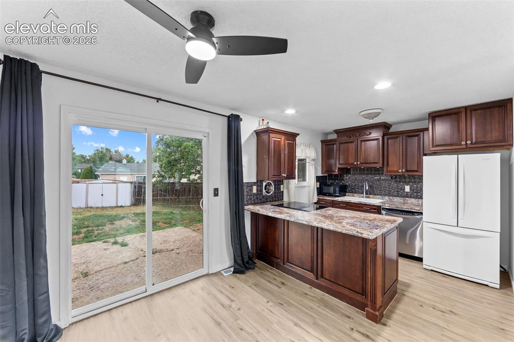 Image 5 of 20: Kitchen featuring a central island, dark wood cabinetry, and stainless stee