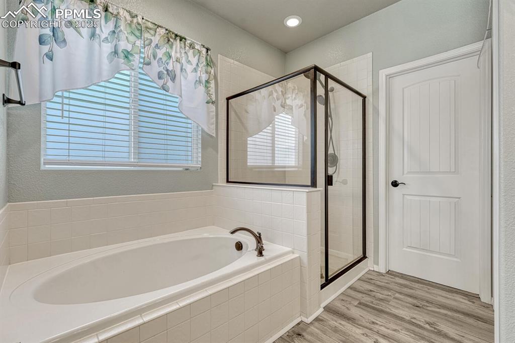 Image 20 of 41: Spacious primary bathroom featuring a garden tub, stall shower, wood finish
