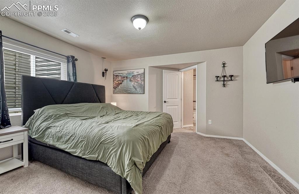 Image 25 of 41: Indulge in relaxation in this bedroom, complete with cozy carpet, a distinc