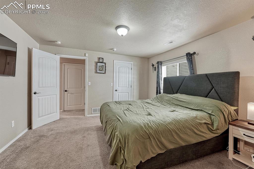 Image 26 of 41: Indulge in relaxation in this bedroom, complete with cozy carpet, a distinc
