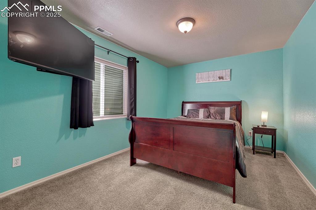 Image 30 of 41: Experience relaxation in this carpeted bedroom, complete with a textured ce