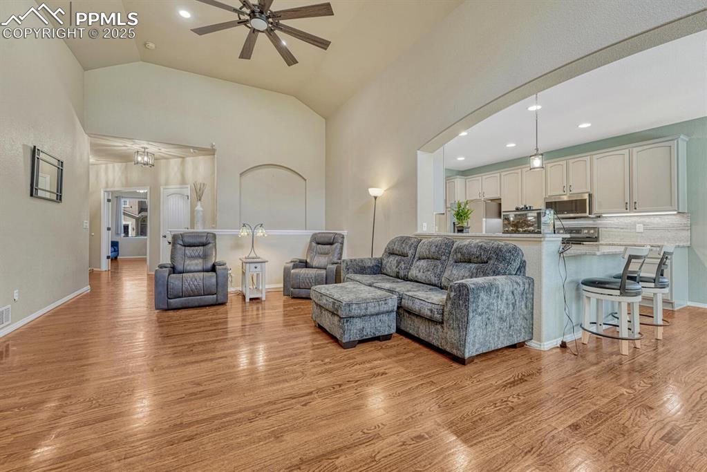 Image 6 of 41: With its ceiling fan, wood floors, and high vaulted ceiling, this living ro