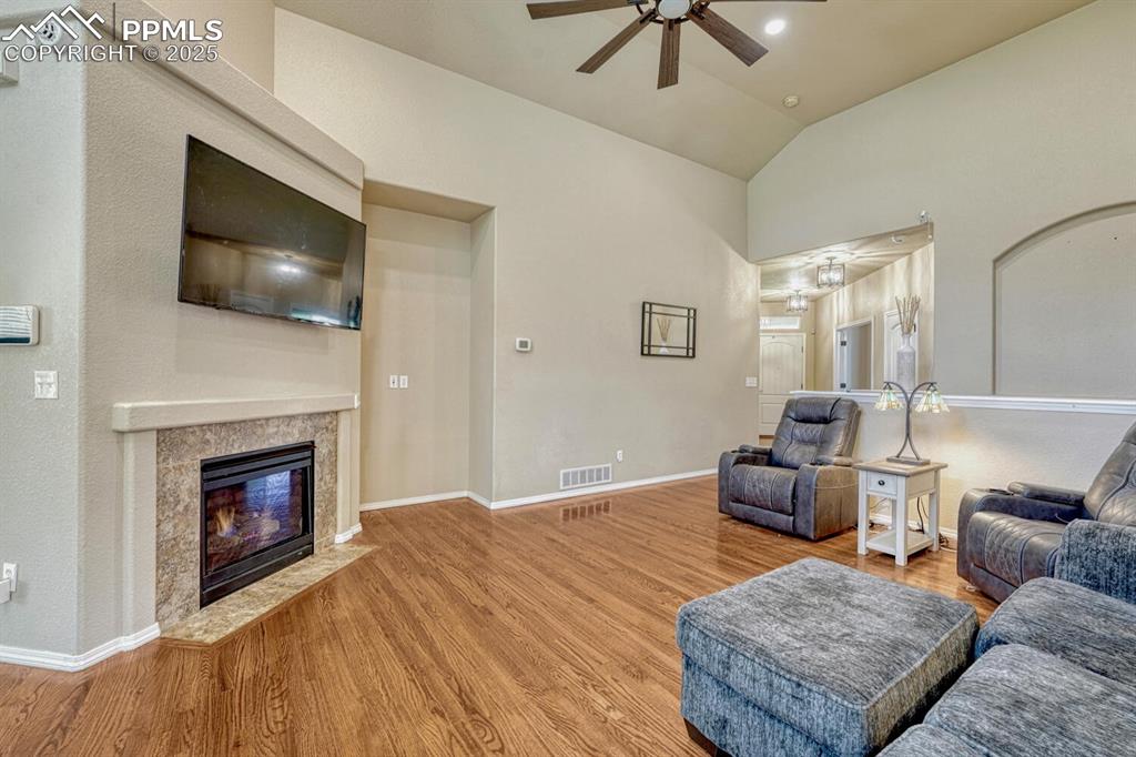 Image 7 of 41: With its ceiling fan, wood floors, and high vaulted ceiling, this living ro
