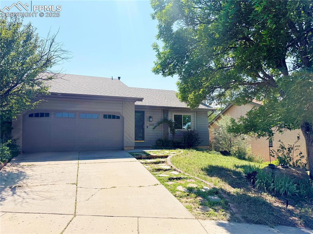 Caption: View of front of home with driveway, a front yard, a garage, and a shingled roof