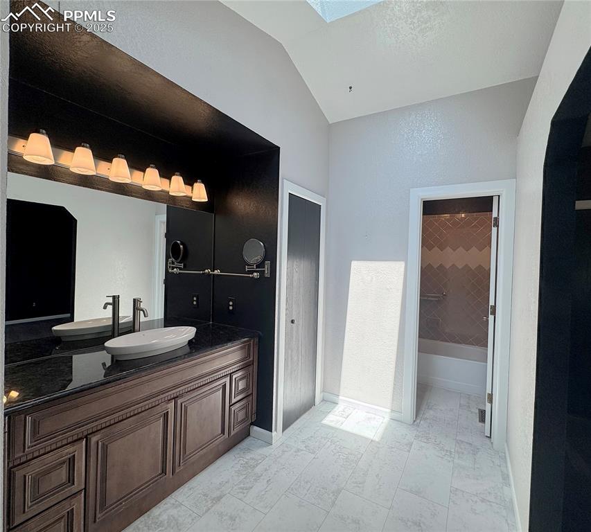 Image 12 of 28: Full bathroom with a skylight, vanity, lofted ceiling, shower / bathtub com