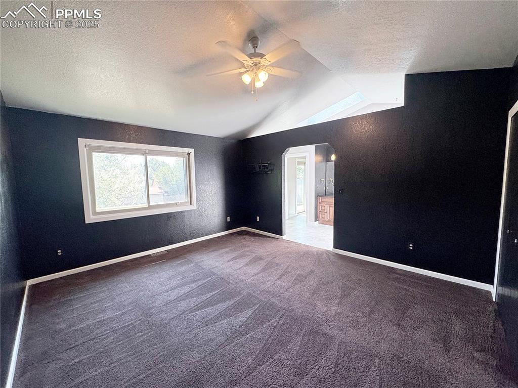 Image 15 of 28: Unfurnished room with a textured ceiling, a textured wall, arched walkways,