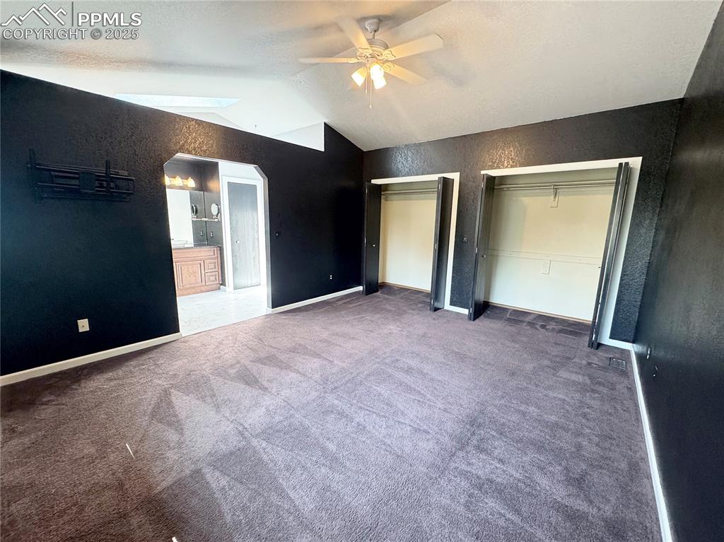 Image 16 of 28: Unfurnished bedroom with two closets, vaulted ceiling, carpet flooring, arc