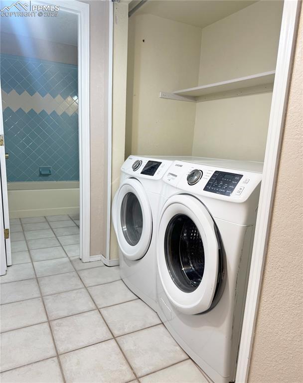 Image 21 of 28: Laundry area with light tile patterned floors and separate washer and dryer