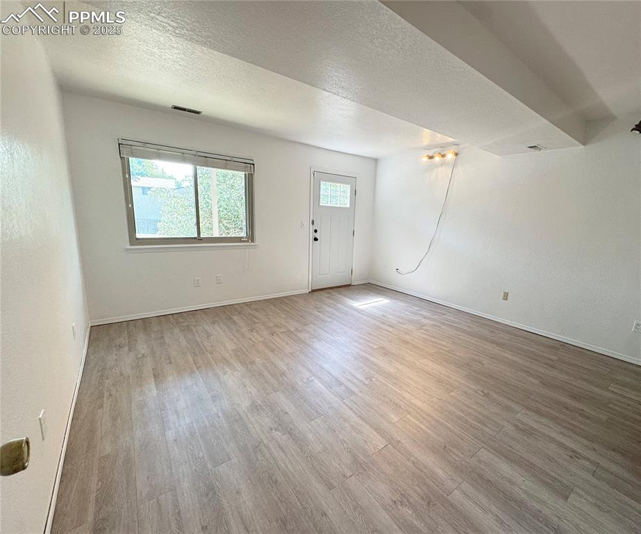 Image 23 of 28: Unfurnished living room featuring a textured ceiling, light wood-style floo