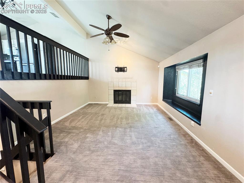 Image 4 of 28: Unfurnished living room featuring carpet, a tile fireplace, ceiling fan, be
