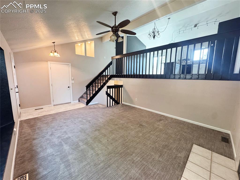 Image 5 of 28: Unfurnished living room featuring a chandelier, carpet, a textured ceiling,