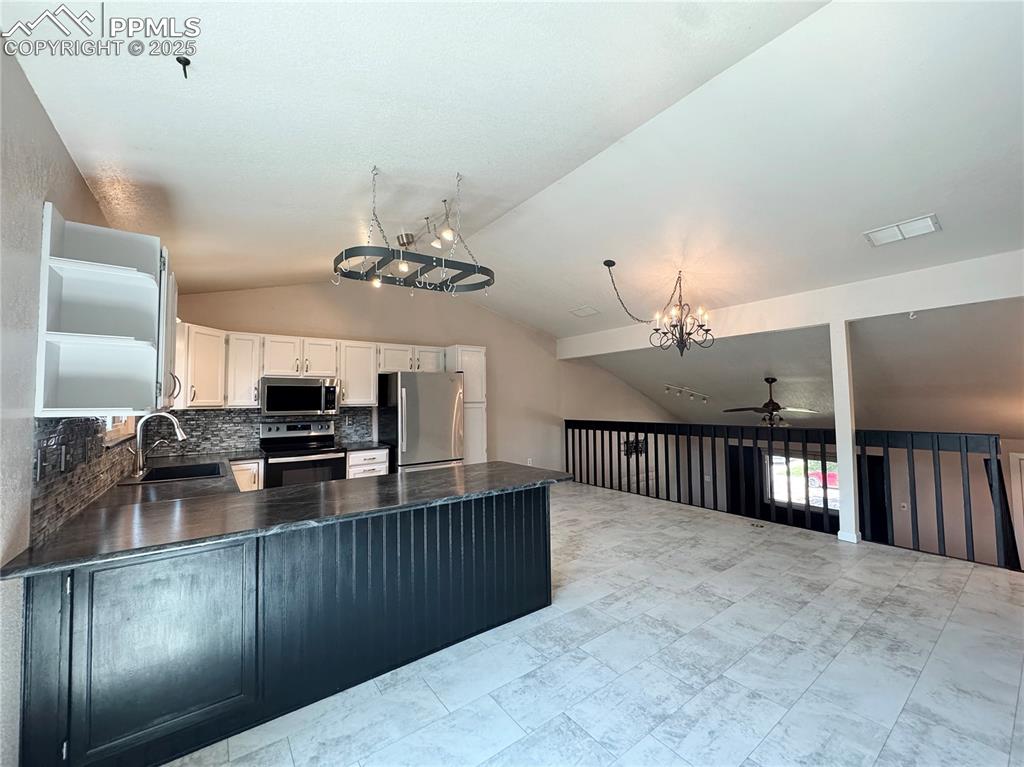 Image 6 of 28: Kitchen with a peninsula, appliances with stainless steel finishes, vaulted