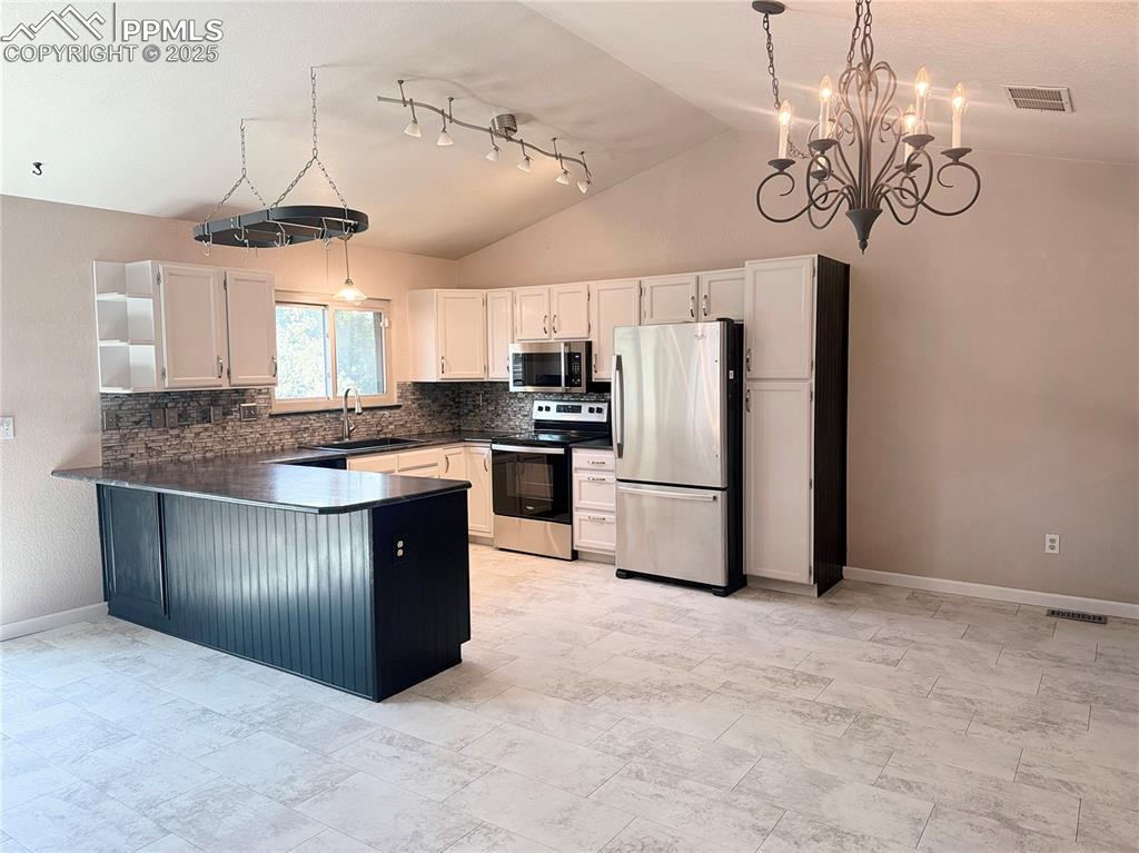 Image 7 of 28: Kitchen with dark countertops, stainless steel appliances, open shelves, a 