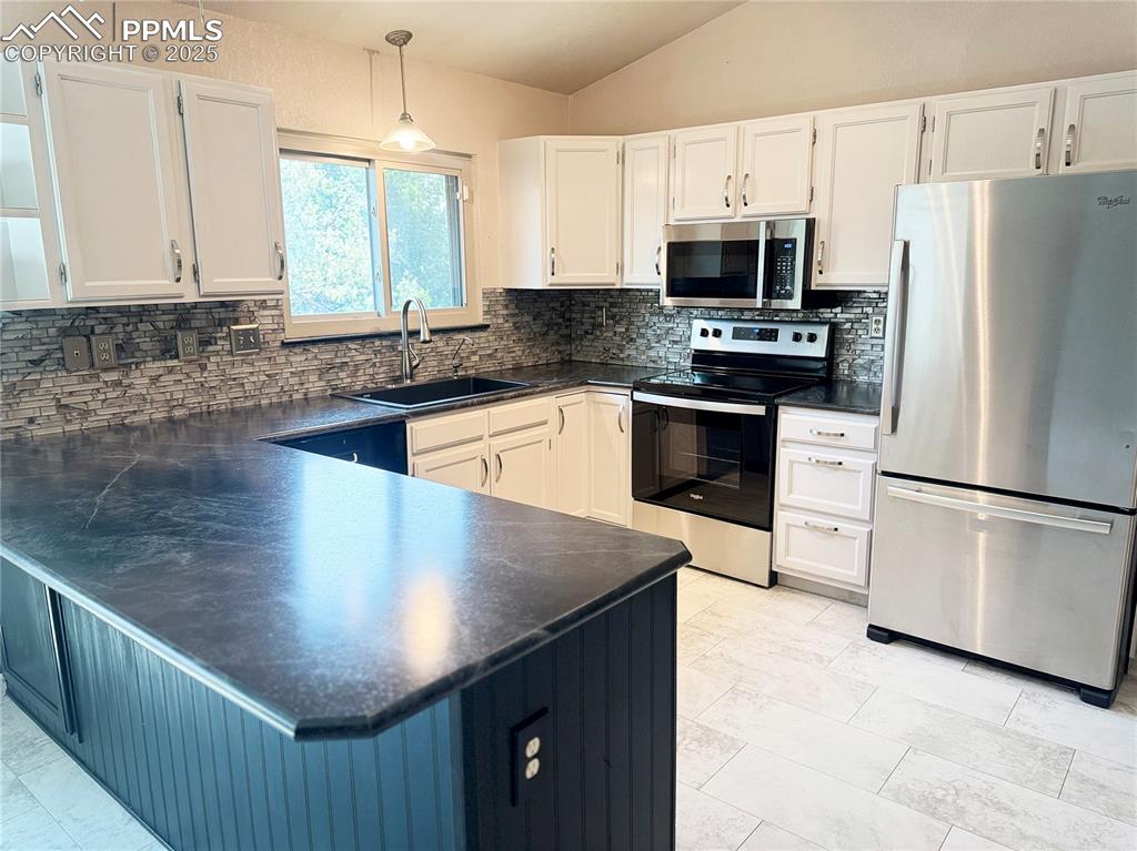 Image 8 of 28: Kitchen with appliances with stainless steel finishes, decorative light fix