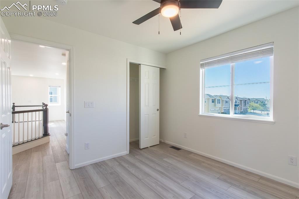 Image 27 of 38: Bright room with wood-finish flooring, a ceiling fan with integrated lighti